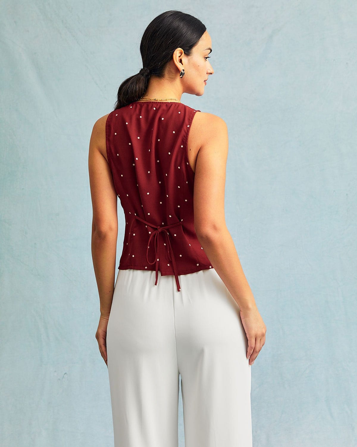 El chaleco sin mangas con cuello de pico rojo y estampado de lunares